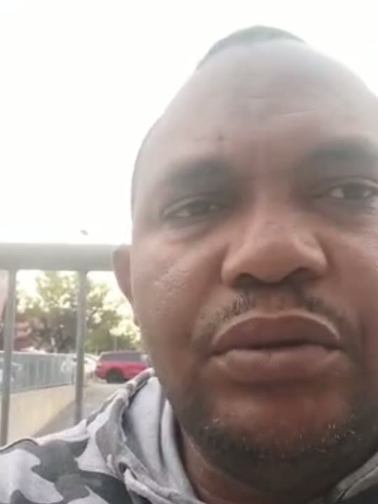 Un des ambassadeurs de la candidature, filmé dans un extérieur, une rue et un grillage derrière