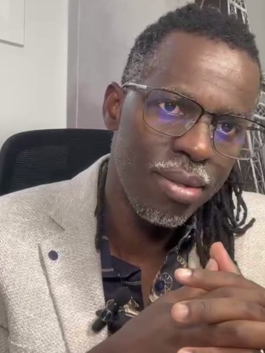 Un des ambassadeurs de la candidature, filmé dans un bureau, lunettes et veste claire
